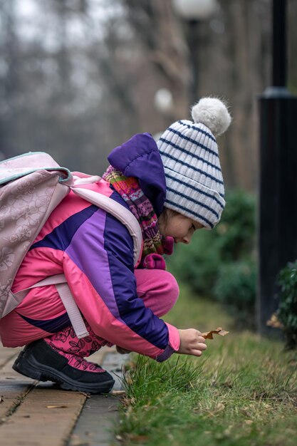 Une petite fille regarde les feuilles en dehors de la saison froide