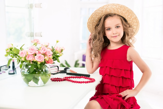 Une petite fille avec une robe rouge et des cosmétiques.