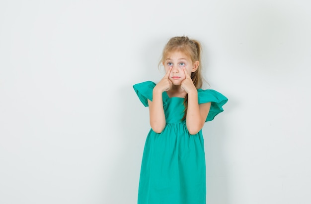 Petite fille en robe verte abaissant ses paupières et à la recherche de silence