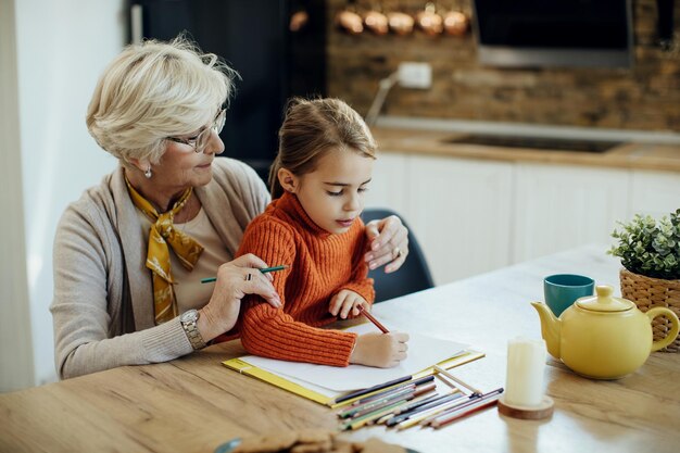 Petite fille et sa grand-mère s'amusant ensemble tout en dessinant sur le papier