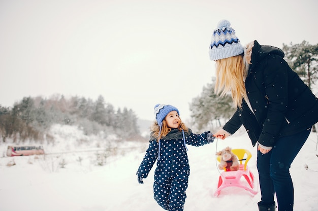 Petite fille avec sa mère jouant dans un parc d'hiver