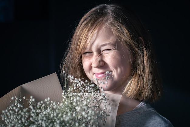 Petite fille satisfaite avec un bouquet de gypsophile sur fond noir