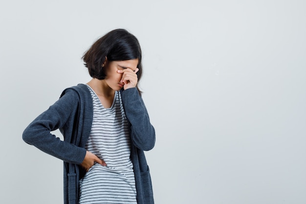 Petite fille se frottant les yeux et le nez en t-shirt, veste et à la fatigue