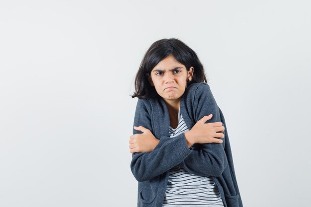 Petite fille se serrant dans un t-shirt, une veste et à l'humble