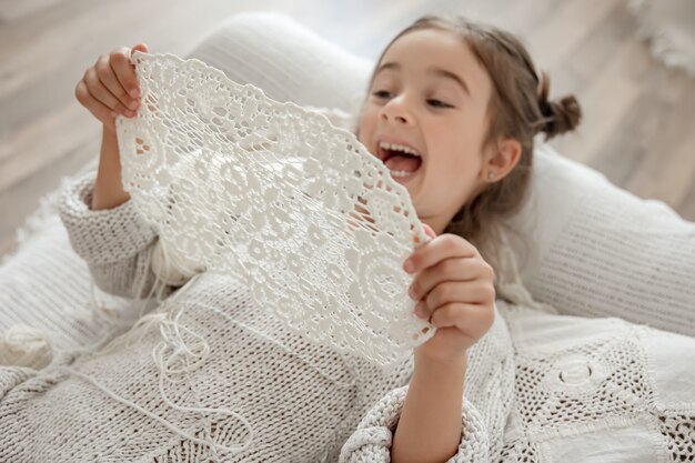 Petite fille avec une serviette en dentelle de fil de coton naturel, crochetée à la main. Crocheter comme passe-temps.
