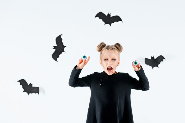 Petite fille sorcière en robe longue noire et accessoires magiques. Halloween.