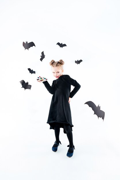 Petite fille sorcière en robe longue noire et accessoires magiques. Halloween