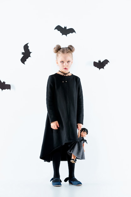 Petite fille sorcière en robe longue noire et accessoires magiques