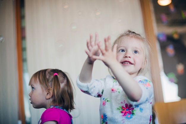 Photo gratuite petite fille souriante attrapant des bulles de savon