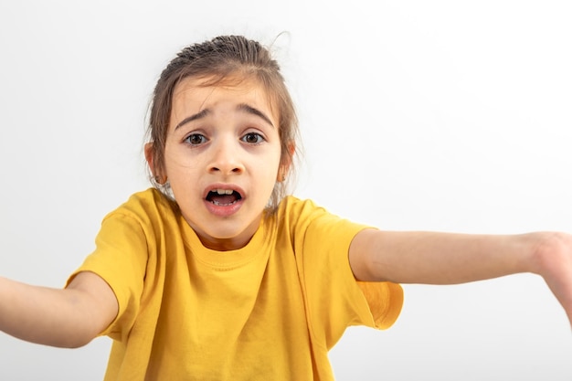 Photo gratuite une petite fille surprise jette ses mains isolées sur un blanc