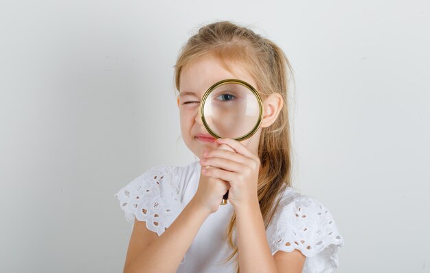 Petite fille en t-shirt blanc à la loupe