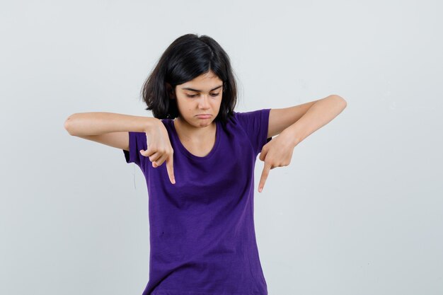 Petite fille en t-shirt pointant vers le bas et à la colère,