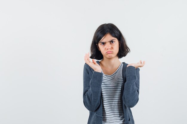 Petite fille en t-shirt, veste montrant un geste impuissant et à la confusion