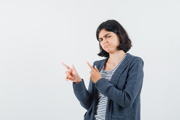 Petite fille en t-shirt, veste pointant vers le coin supérieur gauche et à l'hésitation