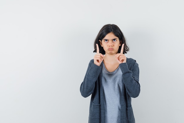 Petite fille en t-shirt, veste pointant vers le haut et à la douteuse