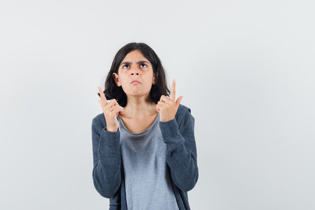 Petite fille en t-shirt, veste pointant vers le haut et à la pensif