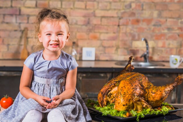 Petite fille sur table avec dinde rôtie