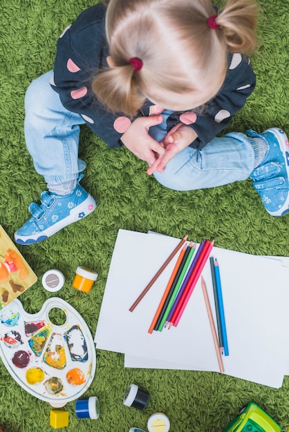 Petite fille sur le tapis avec des crayons