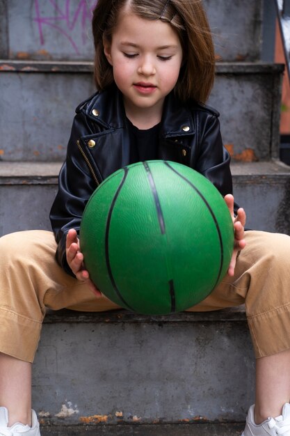 Petite fille tenant une boule verte vue de face