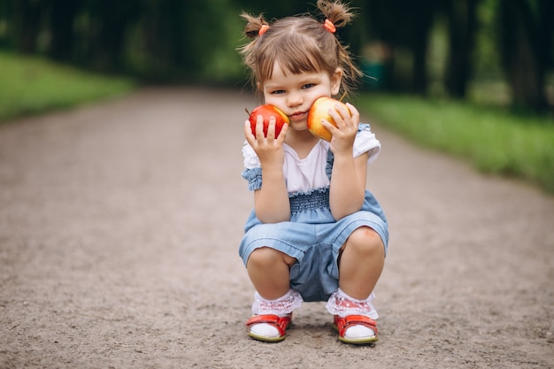 Photo gratuite petite fille tenant deux pommes