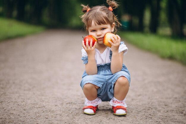 Petite fille tenant deux pommes