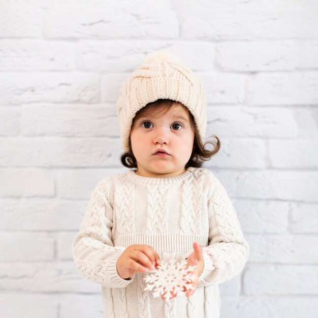 Petite fille tenant un flocon de neige et regardant un photographe