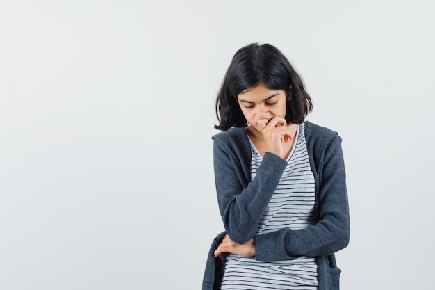 Petite fille tenant la main sur le menton en t-shirt, veste et à la pensif