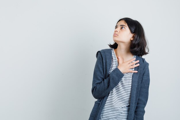 Petite fille tenant la main sur la poitrine en t-shirt, veste et à la peur.