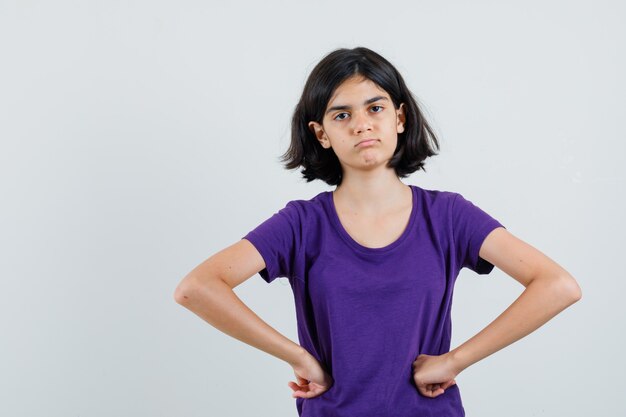 Petite fille tenant les mains sur la taille en t-shirt et à la confusion.