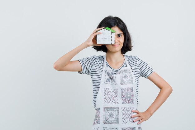 Petite Fille Tenant Le Modèle De Maison En T-shirt, Tablier Et à La Confiance,