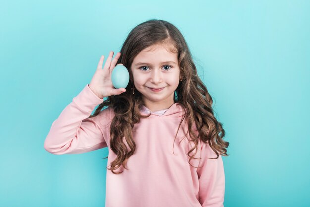 Petite fille tenant un oeuf de Pâques bleu