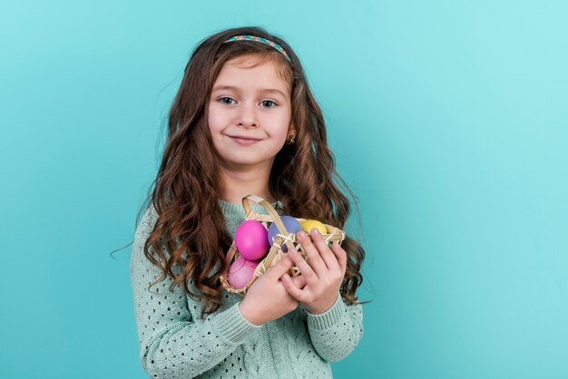 Petite fille tenant un panier avec des oeufs de Pâques