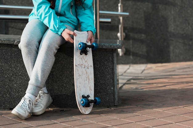 Photo gratuite petite fille tenant une planche à roulettes à côté d'elle