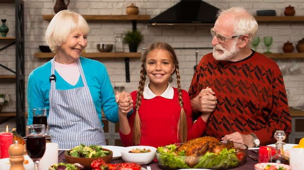 Photo gratuite petite-fille tenant ses grands-parents et regardant la caméra