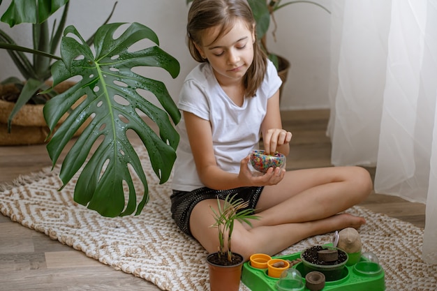 Petite fille tenant un vase avec des perles d'eau multicolores décoratives pour la décoration des plantes.