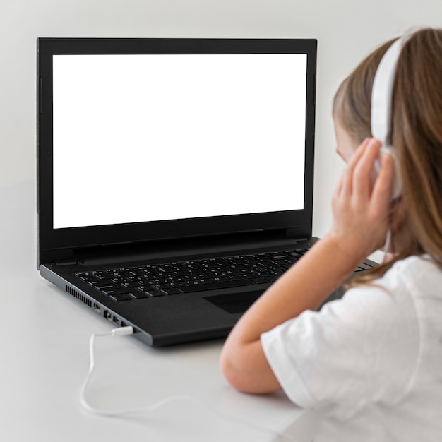 Petite fille utilisant un ordinateur portable avec un casque