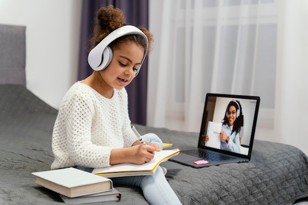 Petite fille utilisant un ordinateur portable pour l'école en ligne