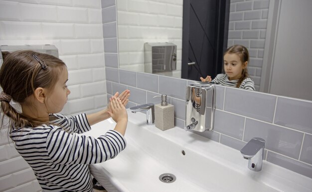 Petite fille utilise du savon liquide pour se laver les mains.