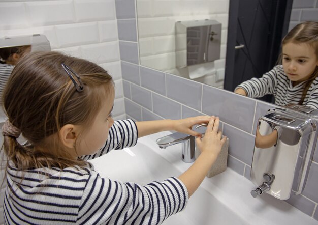 Petite fille utilise du savon liquide pour se laver les mains.