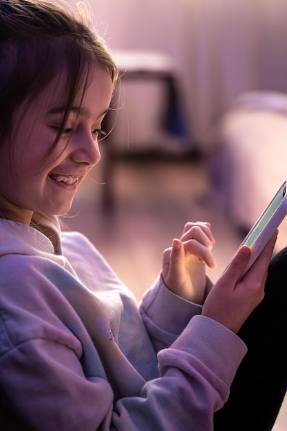 Une petite fille utilise un smartphone alors qu'elle est assise dans sa chambre