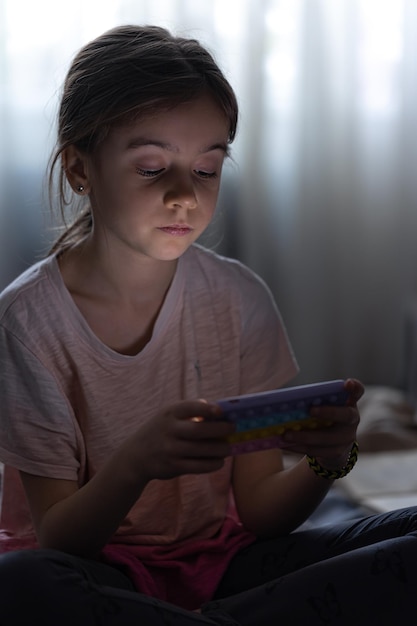 Petite fille utilise le téléphone en étant assise dans son lit le soir