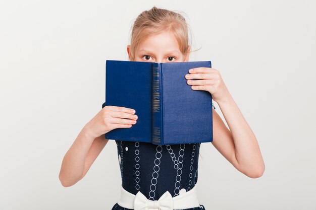 Petite fille avec visage derrière livre