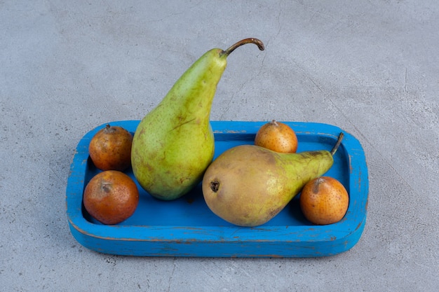 Photo gratuite une petite portion de poires sur un plateau bleu sur fond de marbre.