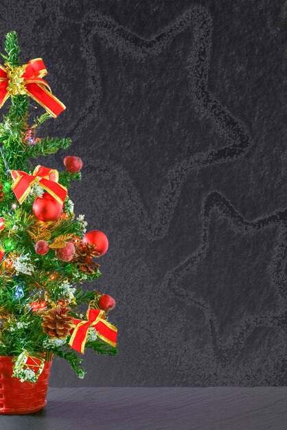 Petite table de sapin de Noël décorée d'ornements rouges et d'arcs sur fond gris