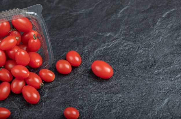 Petite tomate rouge pour la santé, sur fond noir. Photo de haute qualité