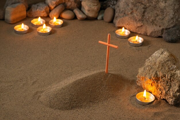 Petite tombe avec des pierres et des bougies allumées autour de la mort funéraire de sable