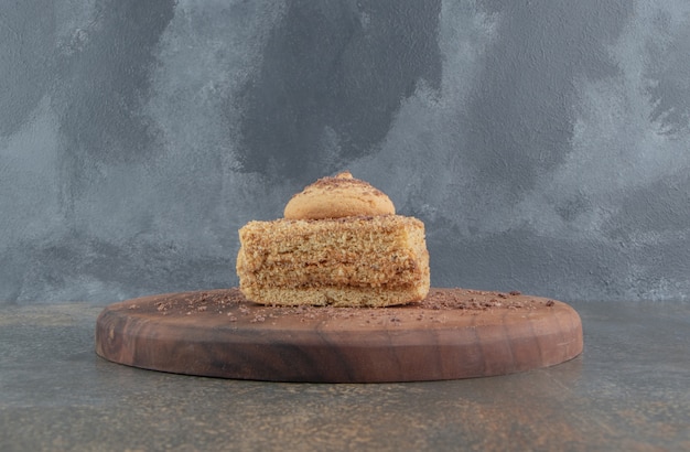 Petite tranche de gâteau garnie d'un cookie sur une planche