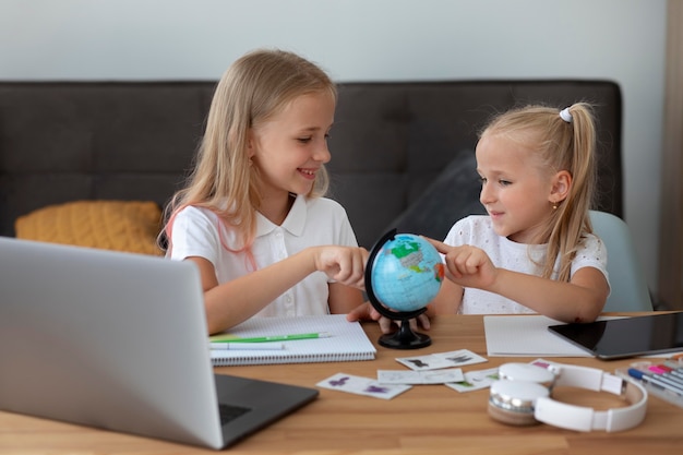 Petites filles faisant l'école en ligne ensemble à la maison