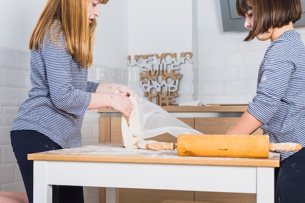 Photo gratuite petites filles rouler la pâte sur la table