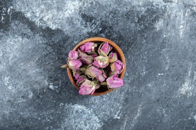 Petites roses en herbe dans un bol en bois.